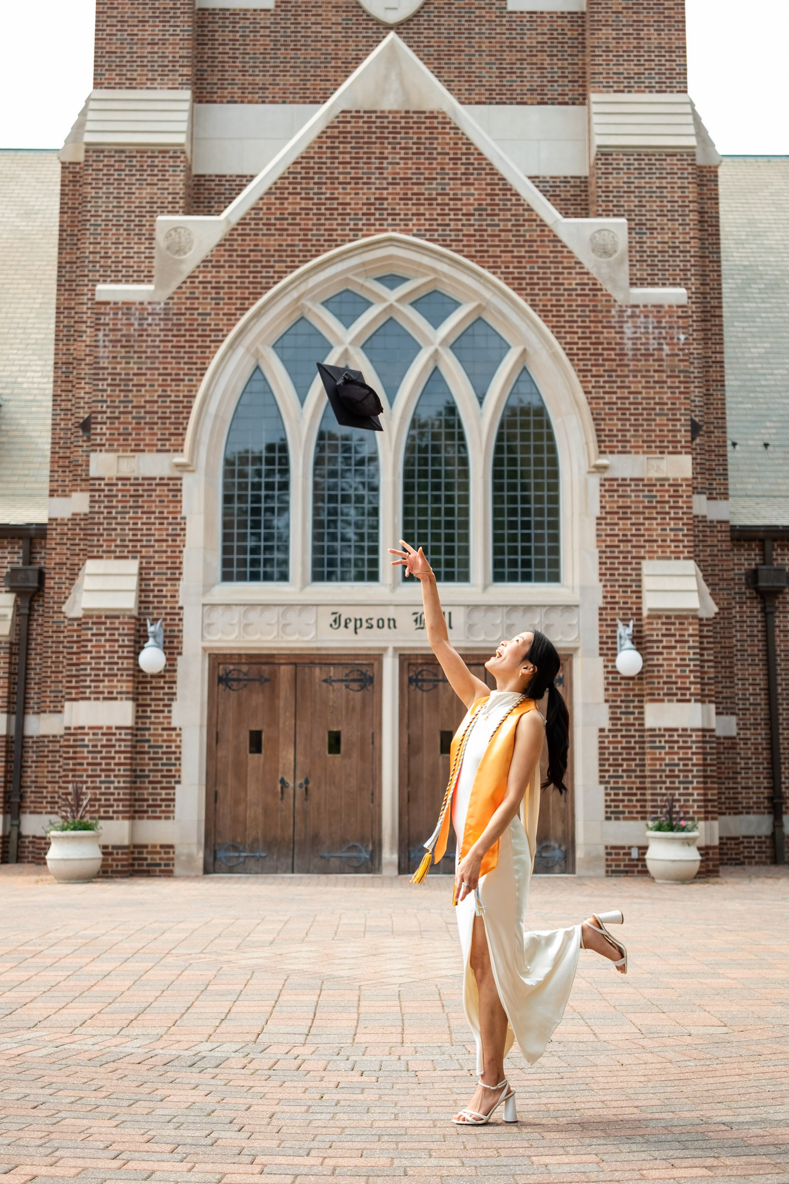 Richmond_Graduation_Photoshoot-12 Graduation photo of girl in white dress throwing cap in the air with gown at the university of richmond.