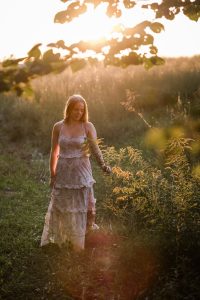 Richmond Senior Photographer Girl holding fern in tall grass at sunset